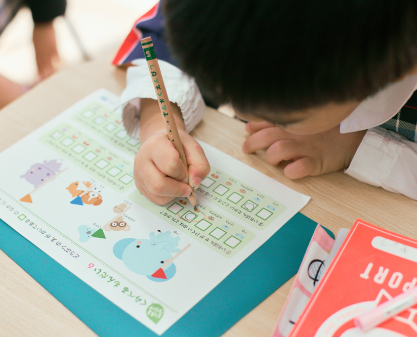 男の子が鉛筆を使ってワークシートに丸を書いています。