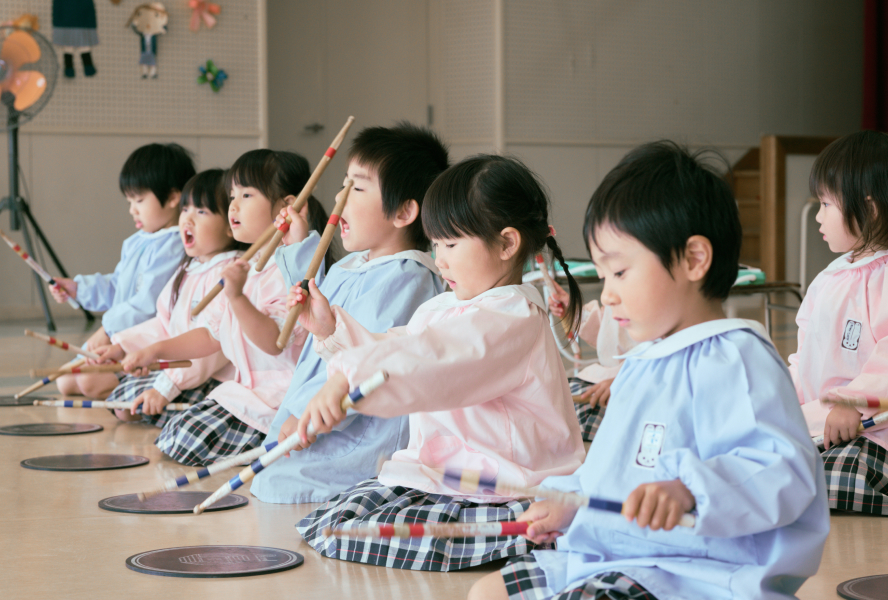 子どもたちが正座をして、薄くて丸い太鼓を叩いています。