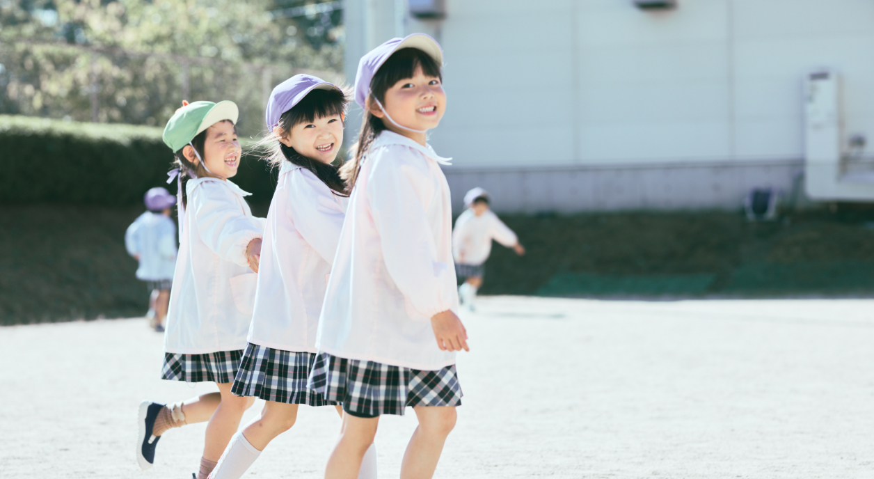 3人の女の子が手を繋ぎながら笑顔で歩いています。
