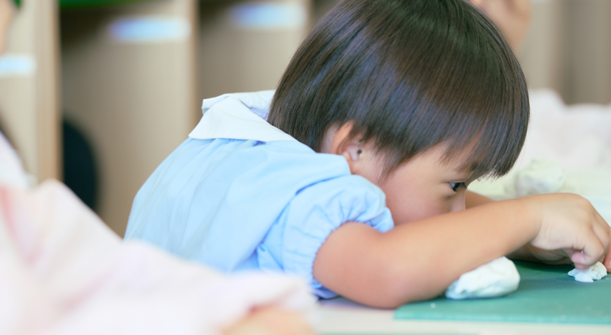 男の子が真剣な表情で粘土で形を作っています。