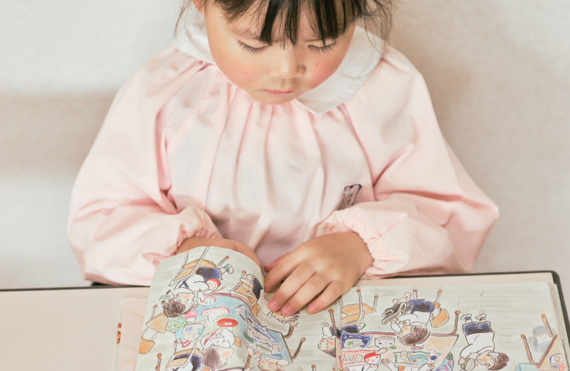 女の子が真剣な表情で絵本を読んでいます。