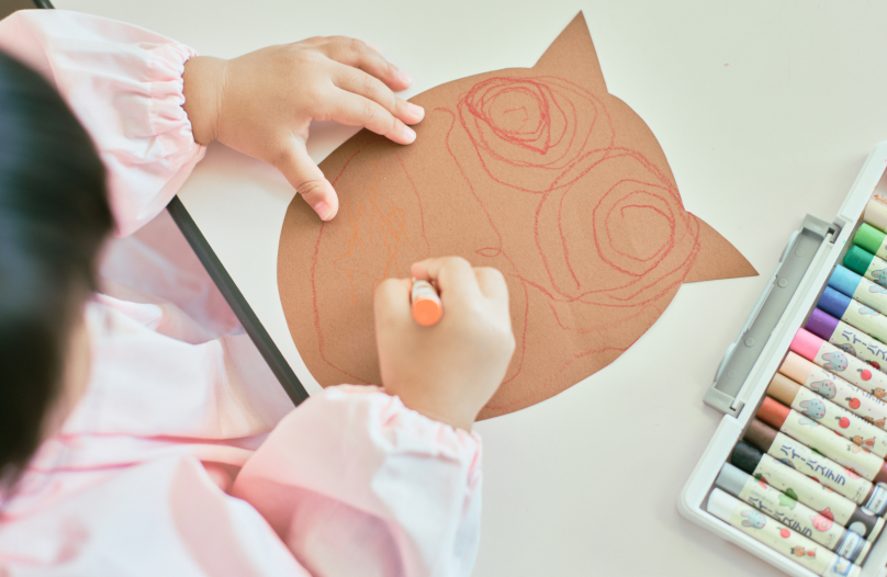 女の子がパステルを使って制作物に絵を描いています。