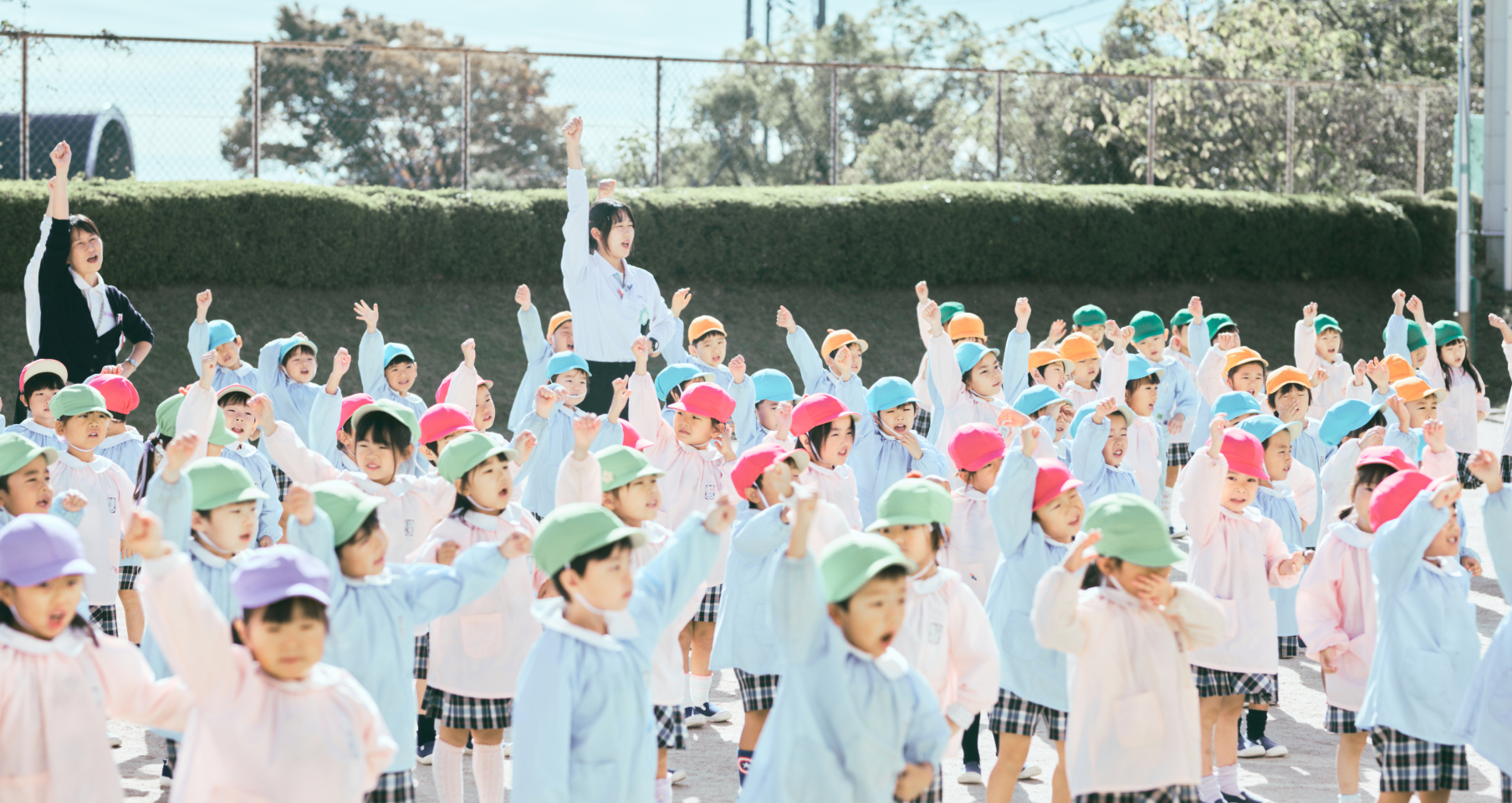 複数のクラスの先生と子どもたちが園庭で体操をしています。