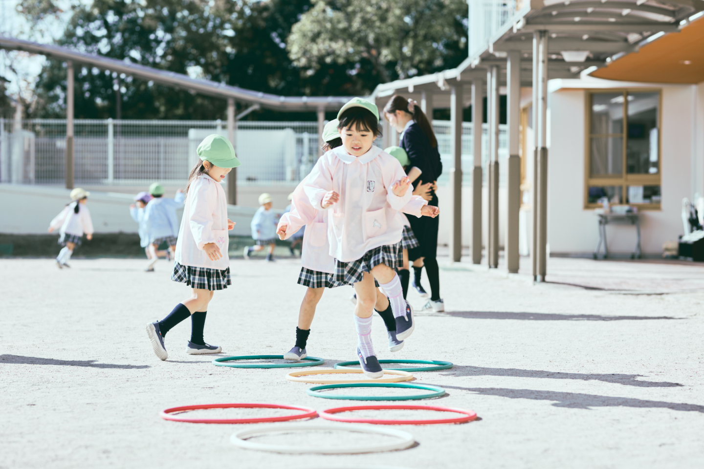 複数の女の子が園庭で運動遊びをしています。